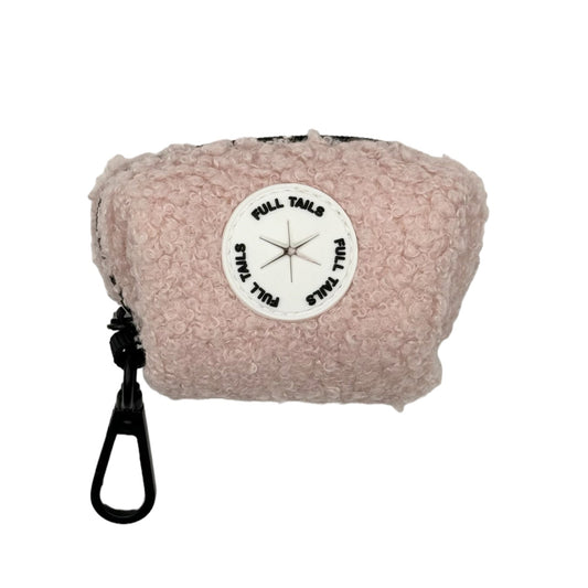 A plush, pink dog poop bag holder with a black strap and a label in the center.