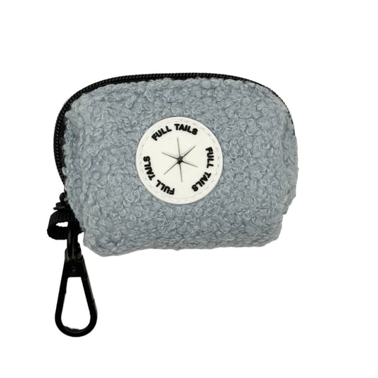 A gray dog poop bag holder with a black strap and a label in the center displaying ' Teddy '.