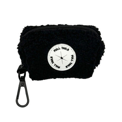 A black dog poop bag holder with a label that reads ' Teddy's Poop Bag Dispenser'. It has a ring for attaching to a leash or belt.