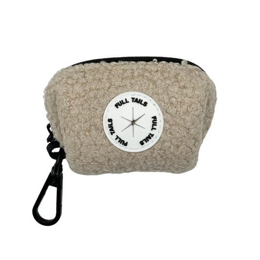 A beige dog poop bag holder with a black strap and a label in the center displaying a compass.